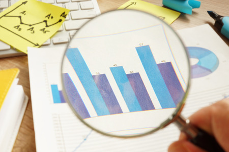 Business audit. Man is looking through magnifying glass on financial charts.の写真素材