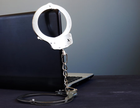 Handcuffs on a laptop. Cyber crime or hacking.の写真素材