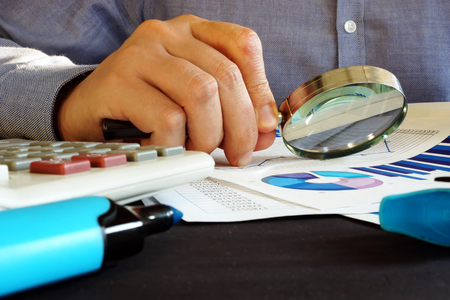 Accountant checking financial report with magnifying glass. Accounting.の写真素材