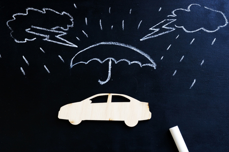 Car insurance. Blackboard with drawn rain and model of car.の写真素材