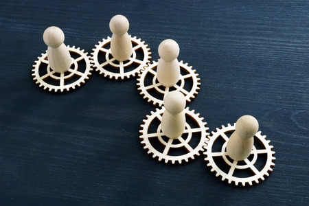 Teamwork success concept. Gear wheels and wooden figures.の写真素材