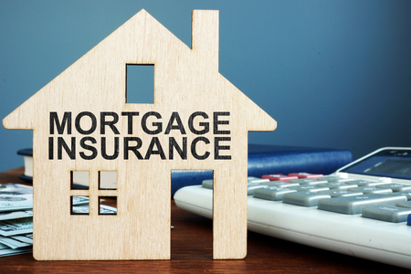Mortgage insurance concept. Wooden home, money and calculator.の写真素材