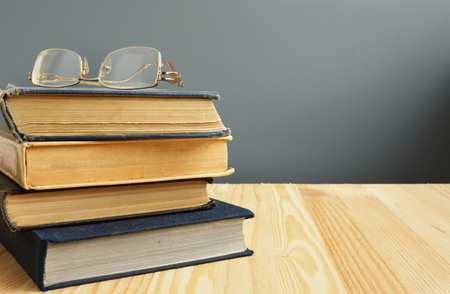 Retro books and old eyeglasses on wooden table.の写真素材