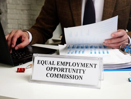 A man works at a table with a tablet Equal Employment Opportunity Commission EEOC.の写真素材