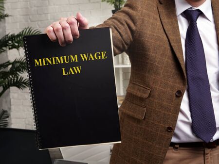 A man in a suit shows a book minimum wage law.の写真素材