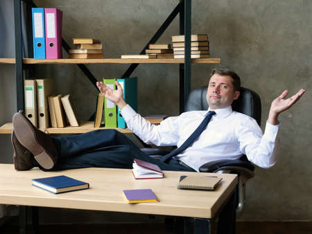 Satisfied businessman celebrates success. The man sits with his feet on the table.の写真素材