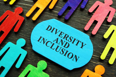 Diversity and inclusion phrase and colored wooden figurines.