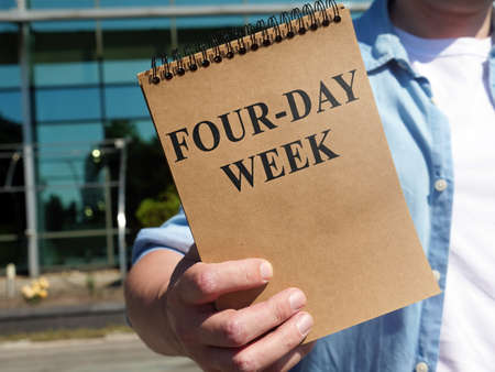Man proposes four-day week sign. Notepad in hand.の写真素材