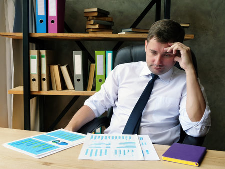 Tired businessman looks at the financial report and audit results.