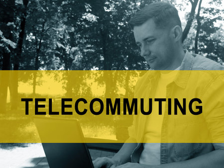 Telecommuting concept. A young man is typing on a laptop in the park.