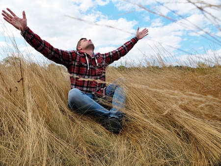 Relaxed calm man stretches out his hands to the sky while sitting in nature. Relaxation and mindfulness.の写真素材