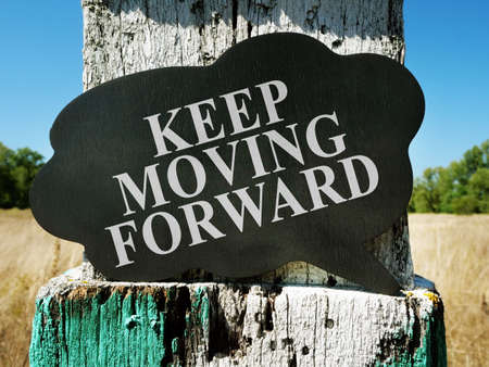 Keep moving forward motivational quote. Old milestone on the field.の写真素材