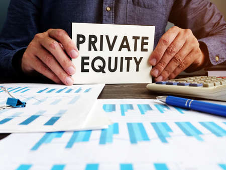Private equity concept. Manager sitting at the table holds an inscription.の写真素材