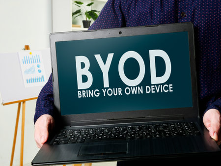 BYOD bring your own device. A man holds a laptop in his hands.