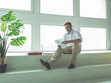 Male businessman works with documents while sitting by the window.