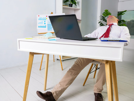 Tired male manager sleeps at the workplace. Overworking concept.の写真素材