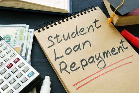 Student loan repayment sign, notepads, calculator and cash.の写真素材