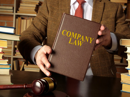 Lawyer holding a company law near table with books.