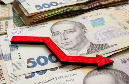 Financial crisis and inflation in Ukraine. Ukrainian money hryvnia and down arrow.の写真素材