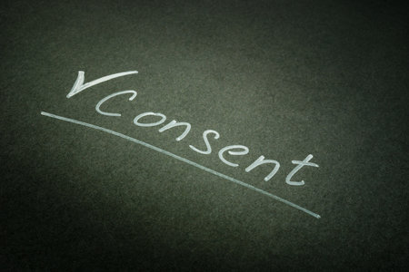 Handwritten consent word on the dark page.の写真素材
