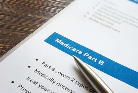 Medicare part B cover list and metal pen.の写真素材