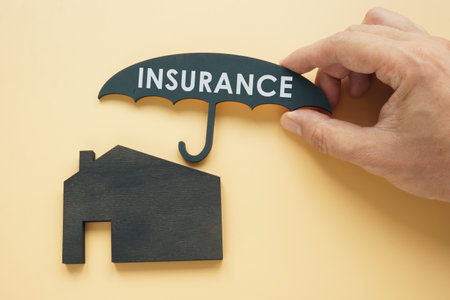 Home insurance concept. Hand holds an umbrella over the house.の写真素材