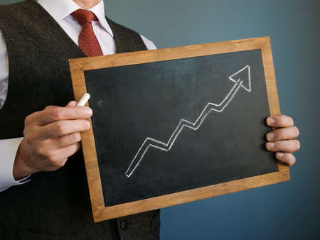 Business success. The manager holds a sign with an upward arrow drawn.の写真素材