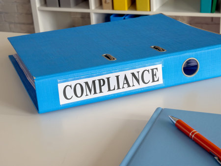 Blue folder with title compliance on the desk.