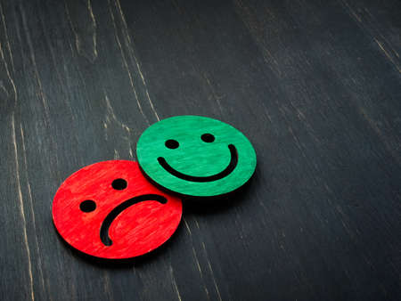 Happy and sad faces on a wooden surface. Review and evaluation concept.の写真素材
