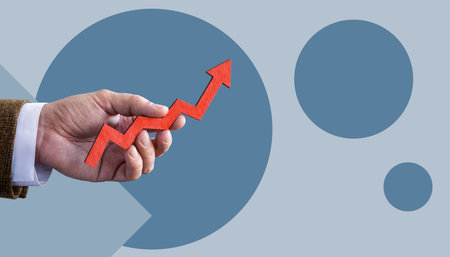 The hand holds a rising arrow. Business growth concept.