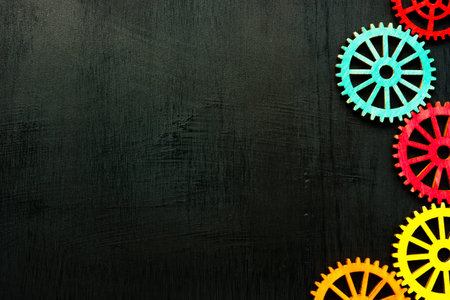 Colorful cog wheels on the dark surface and empty space.
