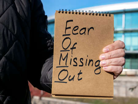 Man holds page with words FOMO fear of missing out.の写真素材