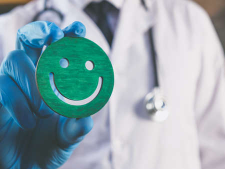 Patient Experience concept. The doctor is holding a smiley as symbol of satisfaction.の写真素材