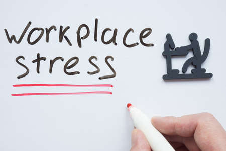 A man writes workplace stress on the whiteboard.の写真素材