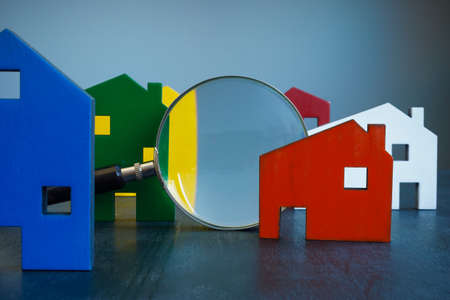 House inspection or selection concept. Colored buildings and a magnifying glass.の写真素材