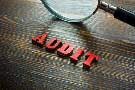 Wooden letters audit and a magnifying glass.