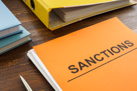 A stack of papers about sanctions and a folder nearby.の写真素材