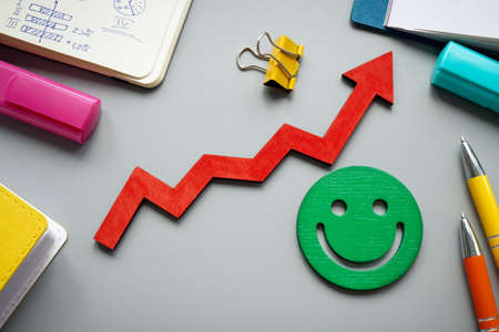 Customer satisfaction and feedback concept. Rising arrow and smiley on the desk.の写真素材