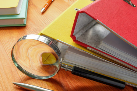 Workplace investigation concept. Folders with papers and a magnifying glass.