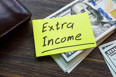 Stack of money and inscription Extra income.の写真素材