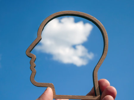 Mindfulness and wellbeing concept. The hand holds the contour of head against sky.の写真素材