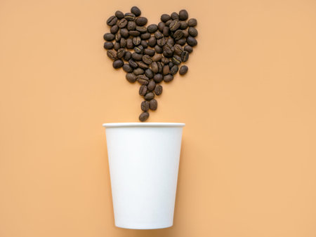 Paper cup and coffee beans in the shape of heart. Minimal modern trendy art.