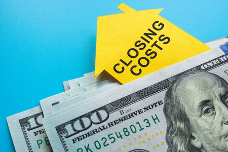 A stack of money and a paper house with an inscription closing costs.