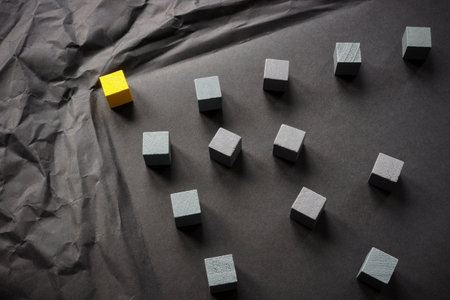 Crumpled paper and a yellow cube as a leader overcomes obstacles.の写真素材