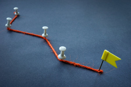 Concept of achieving goals, planning and stages. Orange thread, pins and flag.の写真素材
