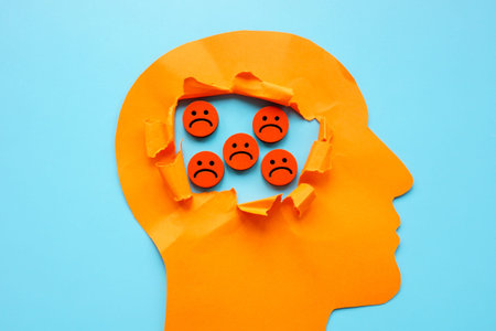 Depression and sad thoughts. Torn paper head and sad emoticons.の写真素材
