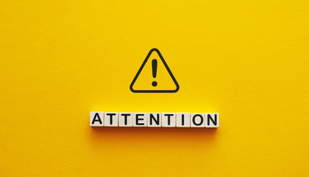 Attention word from cubes with warning icon.