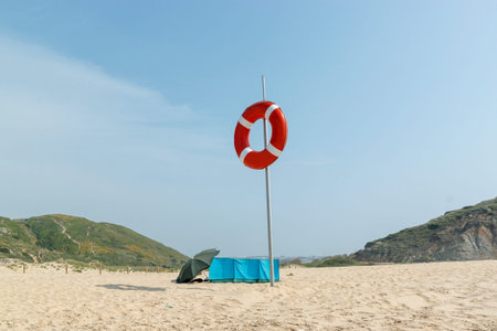 Deserted beach on the Atlantic coast. Lifebuoy on the pole. Neighborhood of Lisbon, Portugal. Summer...