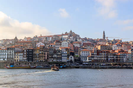 View of the Ribera from the opposite riverside  of the river Douro, Porto, Portugal. Colorful houses of old town on the embankment.  Ferry sailing on the water. Summer sunny day. Travel photography.のeditorial素材
