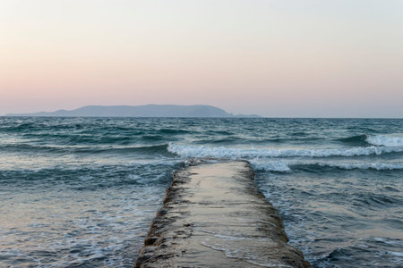 Sea view with an old pier and a view of low mountains in the distance. Kokkini Hani, Crete, Greece. ...